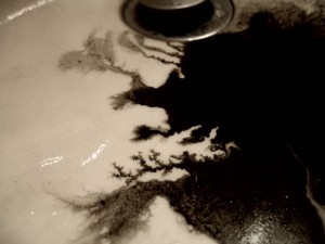 spilled black ink draining away in a wash basin